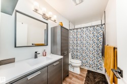 Modern bathroom featuring a wood-finish vanity with a white countertop and integrated sink - 