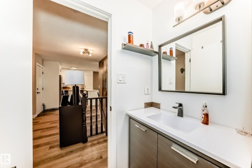 Bathroom vanity featuring a rectangular undermount sink, a dark bronze-toned faucet, and a large rectangular mirror - 10822 11 Avenue, Edmonton, AB 