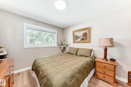 Bedroom featuring a double window with white trim, wood-finish flooring, a flush-mount ceiling light fixture, and light-toned wall paint - 10822 11 Avenue, Edmonton, AB 