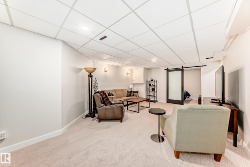 Spacious finished basement featuring recessed lighting, light-toned carpet flooring, and a modern barn door - 10822 11 Avenue, Edmonton, AB 