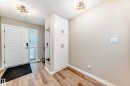 Entryway featuring wood-finish flooring, a white paneled entry door with a frosted glass sidelight, and built-in storage cabinetry - 10822 11 Avenue, Edmonton, AB 