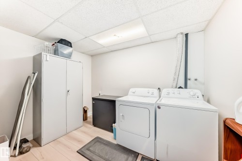 Dedicated laundry area featuring a washer and dryer, light wood-finish flooring, white walls, and a drop ceiling with recessed lighting - 10822 11 Avenue, Edmonton, AB 