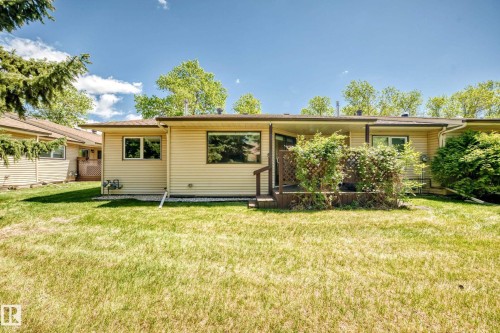 Rear exterior showcasing a wood-finish deck with privacy lattice, surrounded by mature greenery - 10822 11 Avenue, Edmonton, AB 