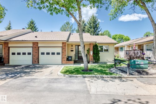 Exterior featuring light-colored siding, brick accents, and a brown shingle roof - 10822 11 Avenue, Edmonton, AB 