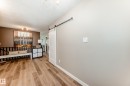 Wood-finish flooring throughout, featuring a white barn door on a black metal track and light gray wall paint - 10822 11 Avenue, Edmonton, AB 