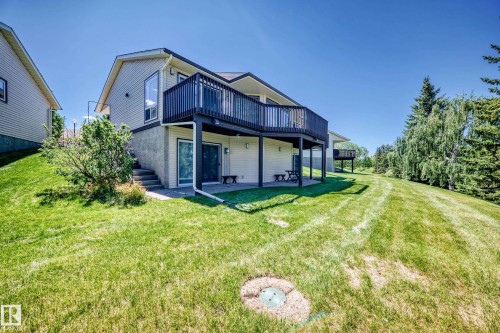Rear exterior featuring a two-story design with a walk-out lower level, an upper-level deck with dark railings, and a lower-level patio area - 10822 11 Avenue, Edmonton, AB 