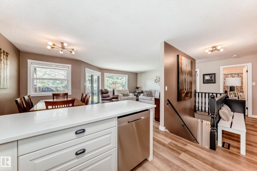 Kitchen island with white cabinetry and integrated stainless steel dishwasher - 10822 11 Avenue, Edmonton, AB 