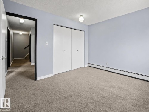 Plush carpeting, bi-fold closet doors, and wall-mounted lighting - #1 13450 Fort Rd Nw, Edmonton, AB - Indoor Photo Showing Other Room