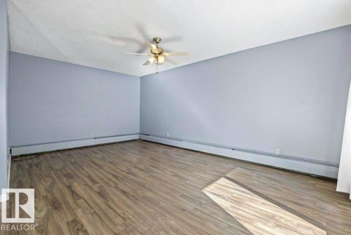 Wood-finish flooring, light blue wall paint, ceiling fan with integrated lighting, and perimeter heating - #1 13450 Fort Rd Nw, Edmonton, AB - Indoor Photo Showing Other Room