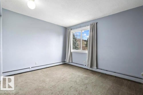 Carpeted flooring, single pane window, baseboard heating, ceiling-mounted light fixture, and light blue wall finish - #1 13450 Fort Rd Nw, Edmonton, AB - Indoor Photo Showing Other Room