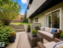 Concrete patio featuring a sliding glass door entry, outdoor wall sconce, and concrete steps leading to a grassy area - 1 13450 Fort Road, Edmonton, AB 