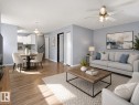 Open-concept living area featuring wood-finish flooring, light blue wall tones, white trim, and a ceiling fan with integrated lighting - 1 13450 Fort Road, Edmonton, AB 