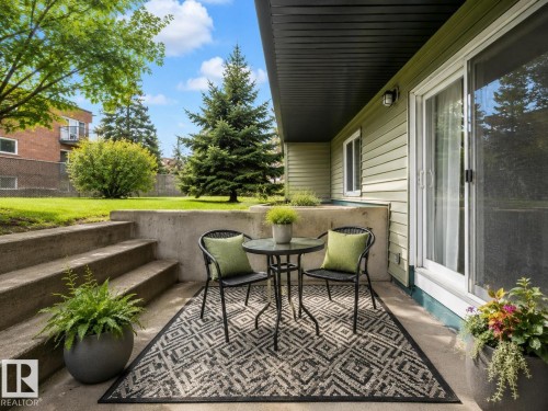 Concrete patio featuring a sliding glass door, step-up access to a grassy yard, horizontal siding, and an overhead awning - 1 13450 Fort Road, Edmonton, AB 