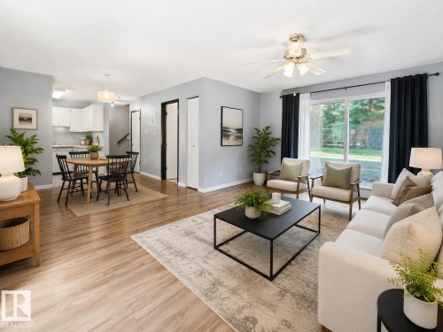 Open-concept living space featuring wood-finish flooring, a dining area with a modern pendant light, and a living area with a ceiling fan - 1 13450 Fort Road, Edmonton, AB 