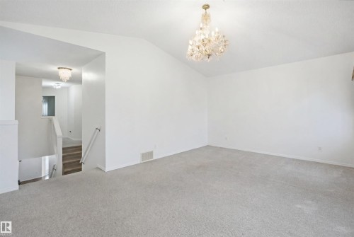 Spacious room featuring vaulted ceilings, a decorative chandelier, and light-toned carpeting - 1560 37B Avenue, Edmonton, AB 