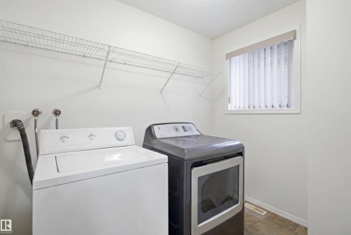 Dedicated laundry area featuring wire shelving, a window with vertical blinds, and tile flooring - 1560 37B Avenue, Edmonton, AB 