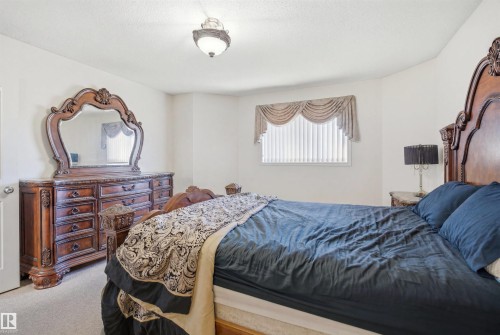 Carpeted bedroom with a window featuring vertical blinds and a draped valance - 1560 37B Avenue, Edmonton, AB 