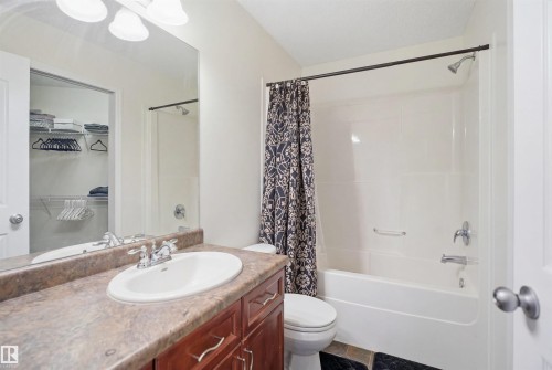 Full bathroom featuring a single vanity with an integrated sink, a brown-toned countertop, and dark wood cabinetry - 1560 37B Avenue, Edmonton, AB 