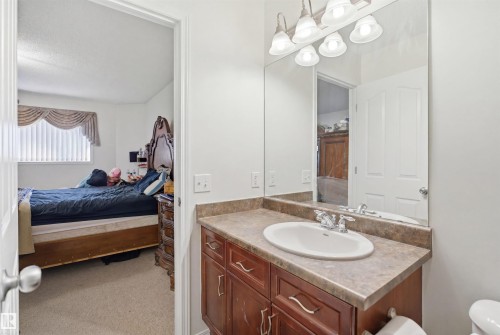 Bathroom vanity featuring a single sink, chrome faucet, and brown wood-finish cabinetry - 1560 37B Avenue, Edmonton, AB 