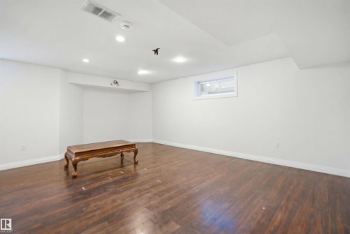 Spacious room featuring wood-finish flooring, recessed lighting, white walls, and a white trim baseboard - 1560 37B Avenue, Edmonton, AB 