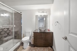 Bathroom featuring a glass-enclosed shower, a vanity with a vessel sink, dark wood-finish cabinetry, and a wall-mounted mirror - 