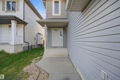 Entryway featuring a covered porch, concrete steps, and a paneled front door with decorative glass inserts - 1560 37B Avenue, Edmonton, AB 