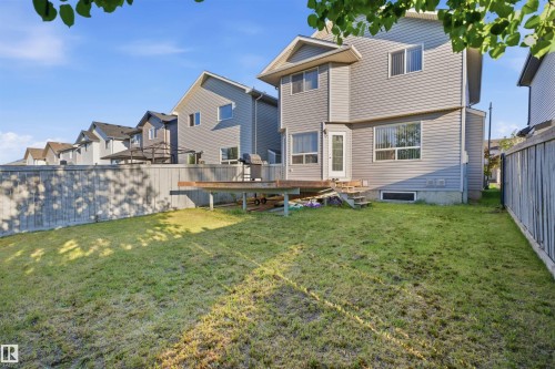 Expansive backyard featuring a manicured lawn, a full wooden privacy fence, and a raised wooden deck with exterior access - 1560 37B Avenue, Edmonton, AB 