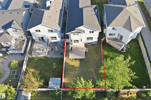 Spacious backyard featuring a multi-level wood deck, manicured lawn, perimeter fencing, and mature trees - 1560 37B Avenue, Edmonton, AB 