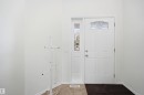 Entryway featuring a white four-panel door with decorative transom window, an accompanying sidelight, and light-toned tile flooring - 1560 37B Avenue, Edmonton, AB 