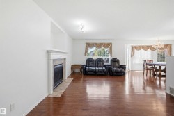 Spacious interior with wood-finish flooring, a fireplace featuring a tile surround and white mantel, and ample natural light from multiple windows - 