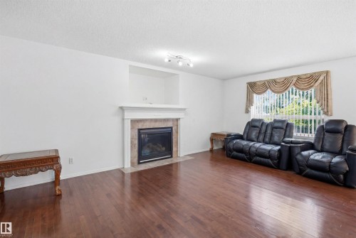 Living area featuring wood-finish flooring and a fireplace with a tiled surround and mantel - 1560 37B Avenue, Edmonton, AB 