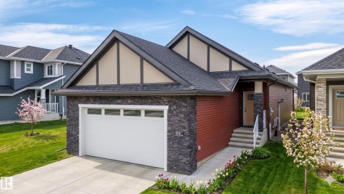 Contemporary residence featuring a dark shingle roof, red siding, and dark stone accents - 3318 Chickadee Drive, Edmonton, AB 