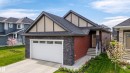 Contemporary residence featuring a dark shingle roof, red siding, and dark stone accents - 3318 Chickadee Drive, Edmonton, AB 