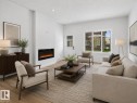 Spacious living area featuring light wood-finish flooring, recessed lighting, and a modern wall-mounted fireplace - 3318 Chickadee Drive, Edmonton, AB 