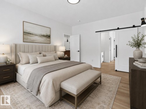 Bedroom with light wood-finish flooring, white walls, and a white barn door - 3318 Chickadee Drive, Edmonton, AB 