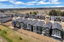 Modern residential development featuring multi-story homes with dark shingle roofs, contrasting exterior siding, and multiple windows - 228 Linden Loop, Leduc, AB 
