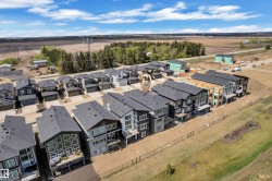New construction residential development featuring multi-level homes with dark roofs and light-colored siding - 