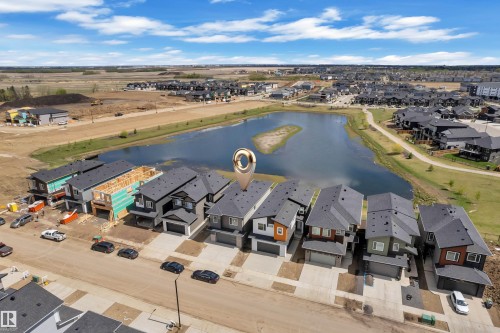 Aerial perspective showcasing a residential street with diverse modern home exteriors, several featuring attached garages - 228 Linden Loop, Leduc, AB 