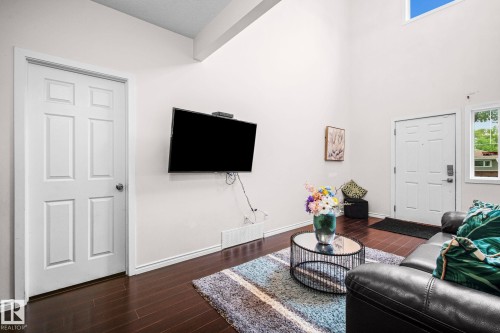 Vaulted ceilings featuring a high window for natural light, dark wood-finish flooring, and white paneled doors - 4806 117 Ave, Edmonton, AB 