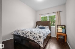 Bedroom featuring dark wood-finish flooring, a large window with white trim, and light-toned walls - 