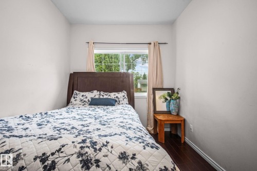 Bright room featuring a window with natural light, dark wood-finish flooring, and light-colored walls - 4806 117 Ave, Edmonton, AB 