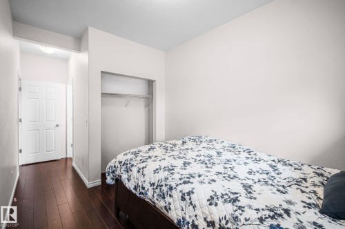 Interior room featuring wood-finish flooring, light-colored walls, and a built-in open closet with shelving and a hanging rod - 4806 117 Ave, Edmonton, AB 