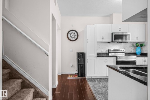 Modern kitchen featuring white cabinetry, stainless steel appliances, dark countertops, and a white tile backsplash - 4806 117 Ave, Edmonton, AB 