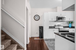 Modern kitchen featuring white cabinetry, stainless steel appliances, dark countertops, and a white tile backsplash - 