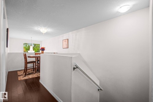 Hardwood-style flooring extends into a bright dining area featuring a window and a chandelier - 4806 117 Ave, Edmonton, AB 