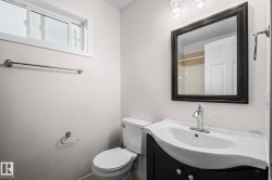 Bathroom featuring a dark wood-finish vanity with an integrated white sink, a framed mirror, and chrome fixtures - 