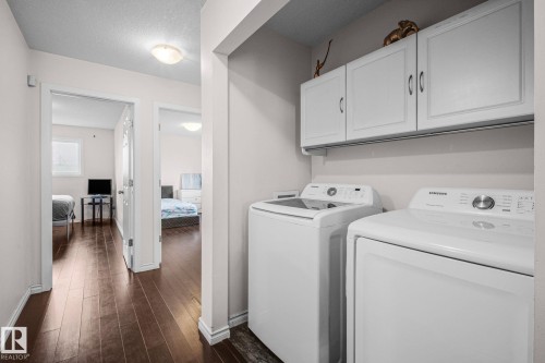 Dedicated laundry area featuring white upper cabinetry and a dark wood-finish flooring - 4806 117 Ave, Edmonton, AB 