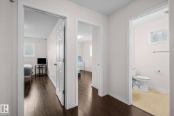 Hallway featuring dark wood-finish flooring, white baseboards, and light-colored walls - 