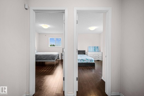 Interior hallways featuring two open doorways, dark wood-finish flooring, light neutral wall paint, and white trim - 4806 117 Ave, Edmonton, AB 