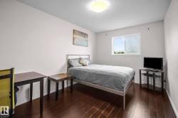 Bedroom featuring dark wood-finish flooring, a white-framed window, and a flush-mount ceiling light - 